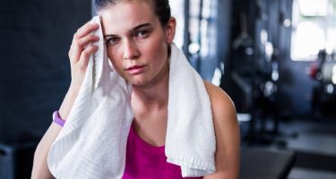 Portrait of young female athlete wiping sweat